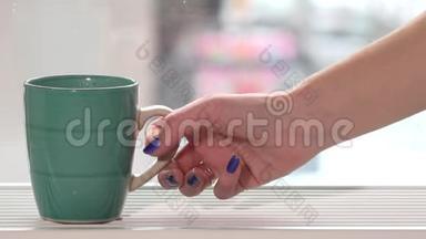 女人的手从窗台上拿一杯热茶。 窗外下雪了。 4K