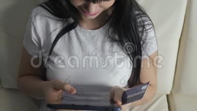 女孩用笔记本电脑数字平板电脑制作<strong>网上销售</strong>购物概念。 黑发女人躺在沙发上看生活用品店