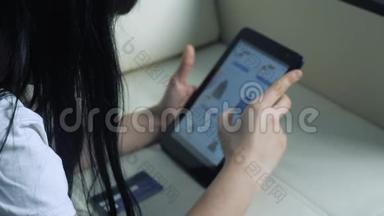 女孩用数字平板电脑制作<strong>网上</strong>购物概念。 黑发女人躺在沙发上看着<strong>网上</strong>商店付钱