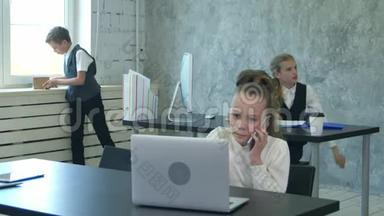 一个<strong>小女孩</strong>在办公室里用手机和笔记本电脑<strong>说话</strong>的肖像