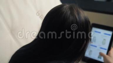 女孩用数码平板电脑打造网上购物概念。黑发女人躺在沙发上看<strong>网店</strong>