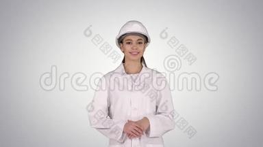 成熟的女工程师戴着安全帽，用手指着产品或文字，在<strong>渐变背景</strong>下行走。