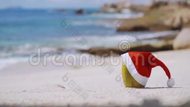 靠近椰子，戴着圣诞老人的<strong>帽子</strong>在热带<strong>沙滩</strong>上，海浪在岩石海岸线上翻滚