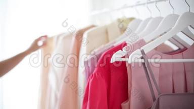 `白色衣架上穿粉色、米色和奶油色的<strong>女式服装</strong>