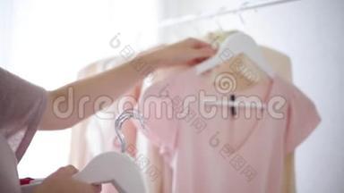 `白色衣架上穿粉色、米色和奶油色的女式服装
