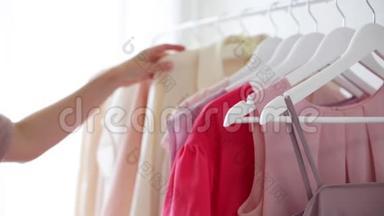 `白色衣架上穿粉色、米色和奶油色的女式服装