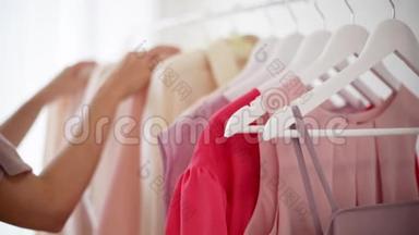 `白色衣架上穿粉色、米色和奶油色的<strong>女式服装</strong>