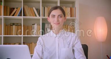 一位年轻的高加索女商人的特写肖像，她正兴高采烈地坐在笔记本电脑前看着摄像机