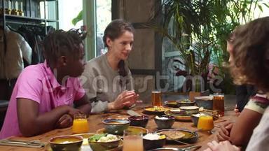 一群多元文化的朋友坐在一起吃午饭，女孩<strong>讲故事</strong>