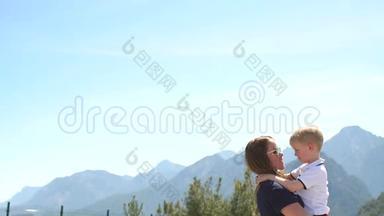 妈妈抱着一个小孩子在她的怀里，在夏天的山上和天空。