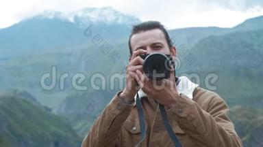 男旅行者摄影师为博客制作专业的山景图片。 一个留着长发和胡子的人
