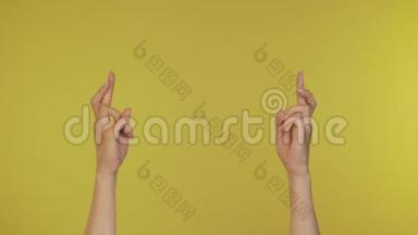 手指交叉的女孩。 年轻时，一个手指祈祷好运的女人，被孤立在黄色的背景上。 4K