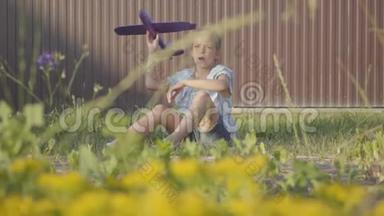 一个漂亮可爱的小女孩坐在篱笆下的草地上发射小飞机的肖像。 孩子<strong>花钱</strong>