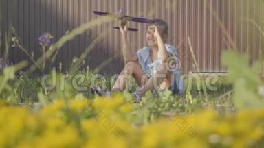 可爱的女孩带着玩具飞机坐在院子里的绿草上。 在户外玩的女孩。 免费儿童