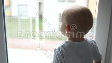 一个穿着白色T恤的两岁小男孩独自在窗外沉思着，说了些什么。 单身子女
