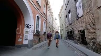 两个年轻的女人在维尔纽斯老城狭窄的街道上走来走去，谈笑风生。