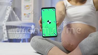 孕妇手里拿着一部带有<strong>模拟</strong>屏幕的<strong>手机</strong>