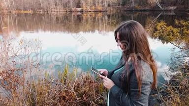 一个<strong>女孩</strong>，在美丽的森林湖畔，在智能手机上的<strong>社交网络</strong>聊天中写道