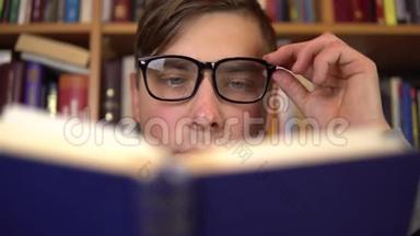 一个年轻<strong>人</strong>正在<strong>图书馆看书</strong>。一个戴眼镜的<strong>人</strong>仔细地看了看这本书的特写镜头。在后台