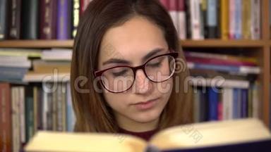 一个年轻的女人正在图书馆看书。 一个戴眼镜的女人仔细地看着这本书的特写。 在里面