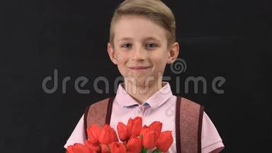 可爱的小男孩带着背包捧着郁金香花束，母亲节快乐，礼物