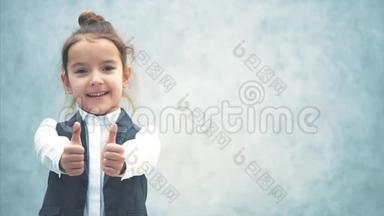 一个灰色背景的小女孩的特写。 在此期间，手势课用两只手显示。 小企业老板。