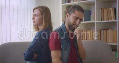 两个愤怒的朋友在争吵中背靠背坐在沙发上，女朋友和男朋友之间发生冲突。