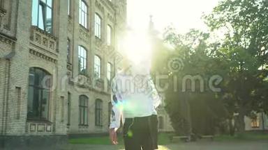 快乐的<strong>年轻人</strong>站在大学大楼前看着相机。 <strong>年轻人</strong>庆祝她的毕业典礼。 太阳。