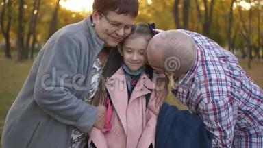 祖父母和<strong>孙女</strong>在秋天公园散步。 爷爷奶奶的特写镜头拥抱小<strong>孙女</strong>