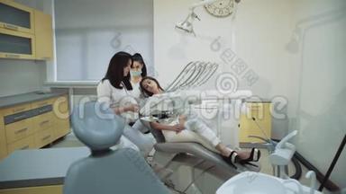 漂亮的女孩在牙科椅上咨询牙医使用x射<strong>线图</strong>像。 4K