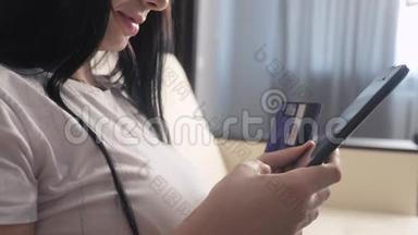 女孩的生活方式使网上销售购物概念与笔记本电脑数字平板电脑。 黑发女人躺在沙发上看着商店