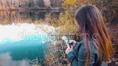 一个<strong>女孩</strong>，在美丽的森林湖畔，在智能手机上的<strong>社交网络</strong>聊天中写道