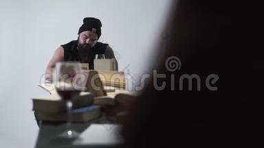 那个长胡子的野蛮男人和穿着黑衣服的年轻女子坐在长桌旁，桌上放着许多书