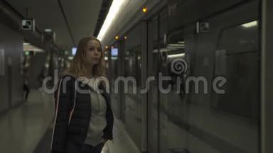 城市妇女在地铁站站台等车。 地下旅行的年轻女子。 穿现代服装的女孩。 城市