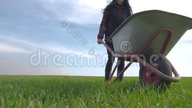 农民女孩红脖子在田里工作，穿着橡胶靴的花园手推车。 农民生态农业耕作收获