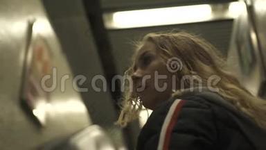 年轻女孩在m现代地铁车站地下移动楼梯。 在城市地铁内的自动扶梯上移动的女人。 办公室