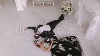 一对为<strong>万圣节</strong>化妆的恐怖夫妇穿着<strong>狂欢</strong>节服装躺在地板上