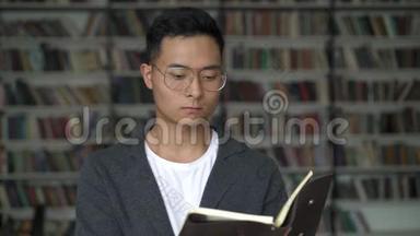 在书架的背景下读着一本便条思考的年轻人