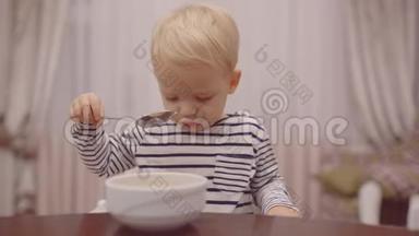 宝宝吃。 快乐的婴儿用勺子吃食物。 美丽的孩子在家吃早餐的肖像。 可爱