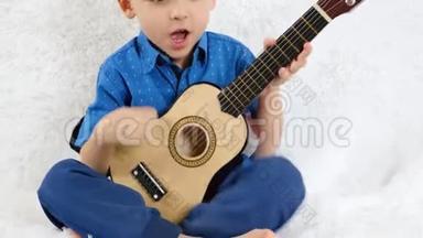 一个小男孩演奏一首儿童`吉他，唱一首歌。 音乐，儿童`教育.. 幸福的概念