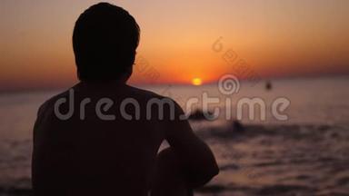 <strong>一个人</strong>独自坐在海滩上的剪影看起来像日落。 <strong>孤独</strong>，思考的人..