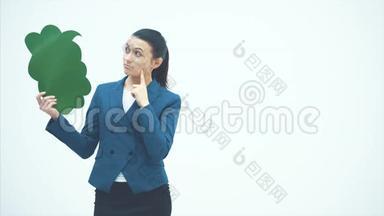 一位漂亮的年轻老师手里拿着一个绿色的弹出。 指着它微笑着。 老师站在白色的背景上。