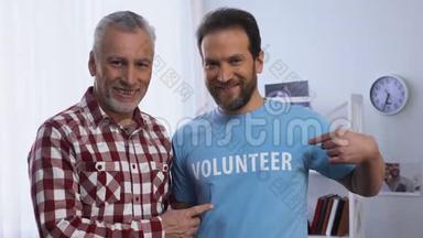 青年和老年男子在t恤上向相机、慈善机构展示志愿者的<strong>话语</strong>