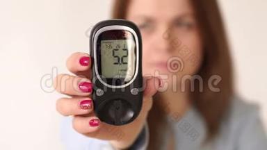 患有<strong>糖尿病的</strong>妇女持有血糖仪，血糖水平很高