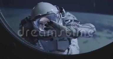 太空人漂浮在太空船的窗户上