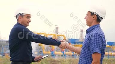 两个人握手工作工程师在一家生产天然气油的加油站工作。 商务商务商务商务