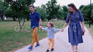 幸福的家庭观念：爸爸妈妈和小男孩在公园散步.. 夏季户外活动