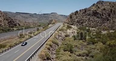 无人机跟随银色MPV汽车行驶在雄伟的阳光明媚的沙漠岩石山道路上阳光明媚的夏季亚利桑那州，美国度假。