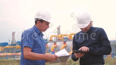 两名工程师在一家生产天然气的天然气工厂工作。 行业业务团队合作理念。 工人和工程师