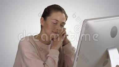一个穿粉<strong>红色</strong>套头衫的金发女孩看着电脑显示器在<strong>渐变</strong>背景下观看视频。